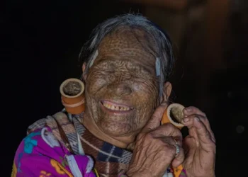 Elderly tattooed Chin tribal woman with large ear gauges smiling, Myanmar