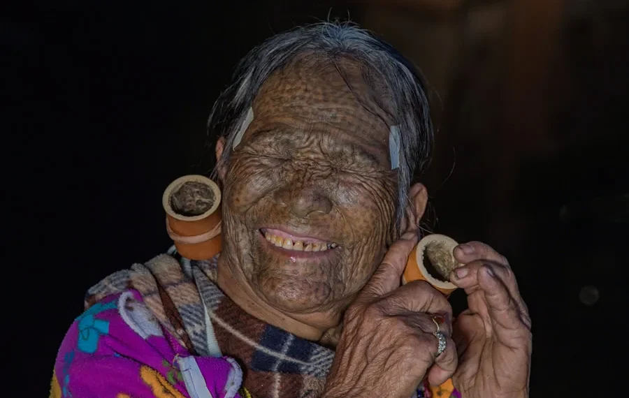 Elderly tattooed Chin tribal woman with large ear gauges smiling, Myanmar