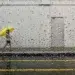 Famous street photographers capturing a person with yellow umbrella through a rain-covered window
