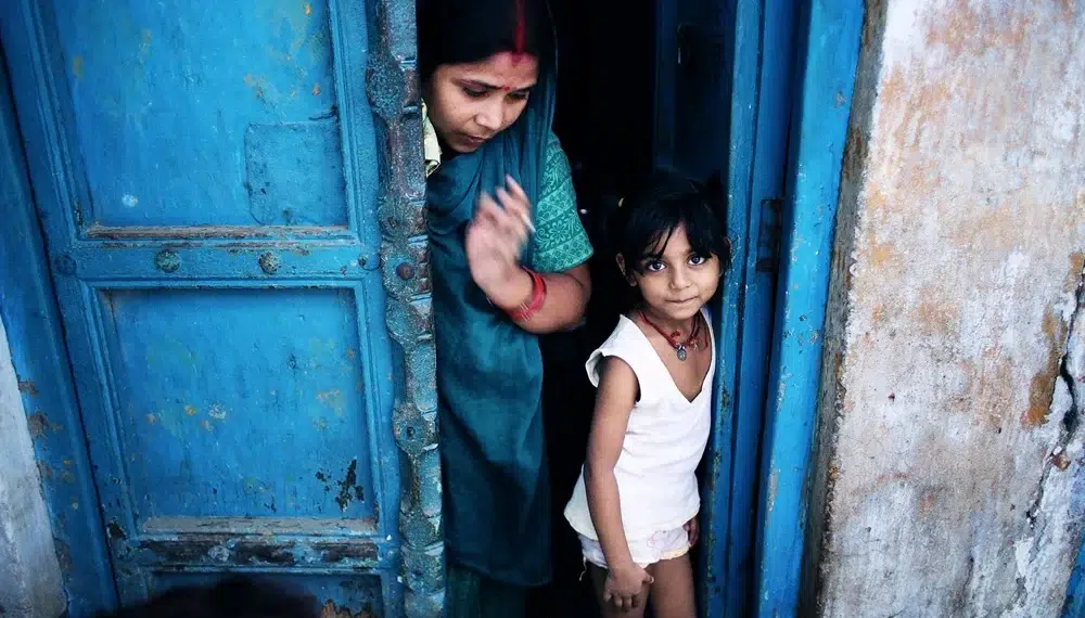 A woman in a blue sari and a young girl standing in a blue doorway