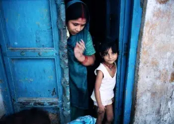 A woman in a blue sari and a young girl standing in a blue doorway