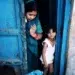 A woman in a blue sari and a young girl standing in a blue doorway