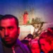 Crowd watching a woman in red sitting on a staged installation indoors