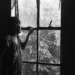 Elderly woman gazing through a rain-streaked window, black and white