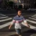 Man walking across sunlit city crosswalk at intersection