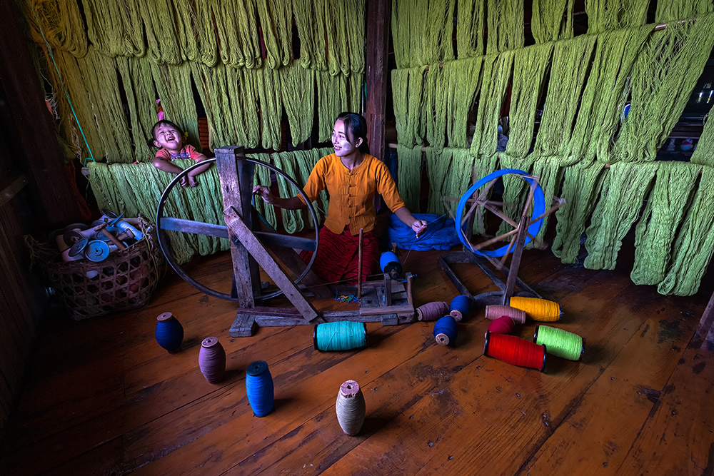 A women weaving inside a house with her daughter enjoying in Inle lake, Myanmar