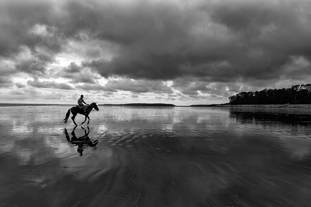 Horseman riding the reflecting beach of Udaypur after rain