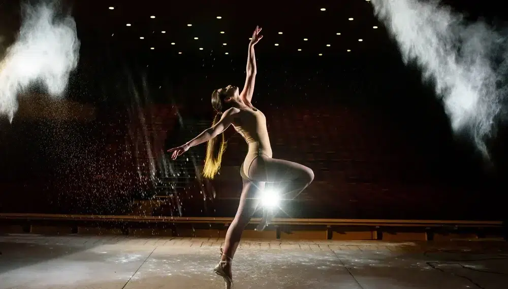Dancer performing on stage with dramatic lighting and smoke