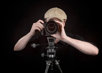 Photographer taking a photo with DSLR camera on tripod against dark background