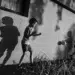 Street photographer captures two boys playing football against a wall with dramatic shadows