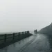 Two figures walking a misty coastal path beside a stone wall, Ireland