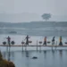 Villagers carrying basket yokes across a bamboo bridge in misty Bangladesh winter