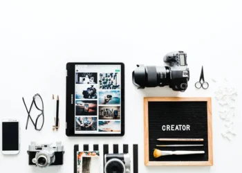 Flatlay of cameras, tablet, phone, and a letter board reading "CREATOR"