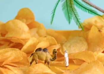 Miniature camel and figure standing among potato chips styled as a desert scene
