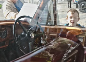 Boy peering into a vintage car window, candid street photography