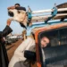 Men handling a camel loaded onto a truck at market