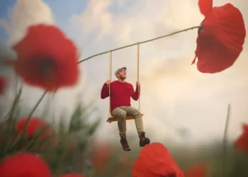 Man swinging from a giant poppy stem in a surreal flower field