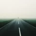 Person walking alone on a foggy road through open landscape