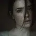 Moody close-up portrait of a freckled woman with hair across her face