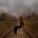 Patty Maher photography of a red-haired woman sitting on a chair on railway tracks