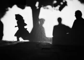 Child and adult shadows cast on a bright white wall, black and white