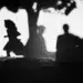 Child and adult shadows cast on a bright white wall, black and white