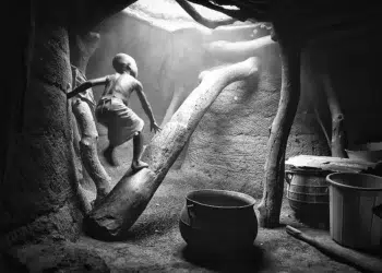 Child climbing in a rustic hut, african tribes photos in black and white