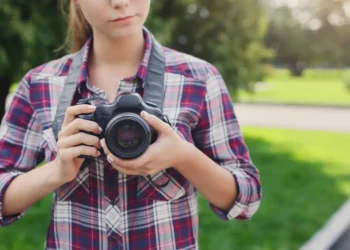 Young woman holding DSLR camera outdoors in a park