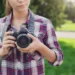 Young woman holding DSLR camera outdoors in a park