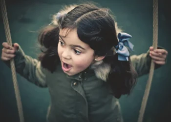 Little girl on a swing with a surprised expression outdoors