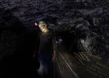 Coal miner with headlamp inside a dark underground tunnel in Jharkhand, India