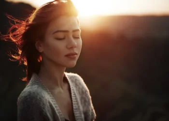 Woman with closed eyes in warm sunset light outdoors