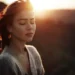 Woman with closed eyes in warm sunset light outdoors