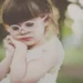 Little girl with pink glasses resting her head in soft natural light