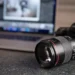 Canon DSLR camera and lens on a desk with a laptop showing photo editing