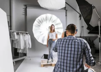 Photographer shooting a female model in a studio with umbrella lighting