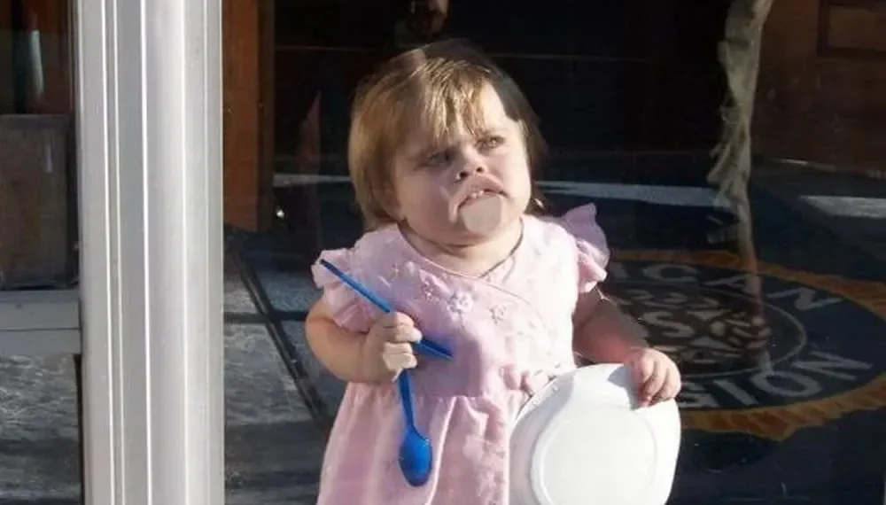 20 Funny Photos Of Parenting That Will Make You Laugh 21 Toddler in pink dress holding a spoon and bowl with food on her face — funny parenting pictures