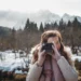 Woman using a Polaroid camera outdoors in a snowy mountain landscape
