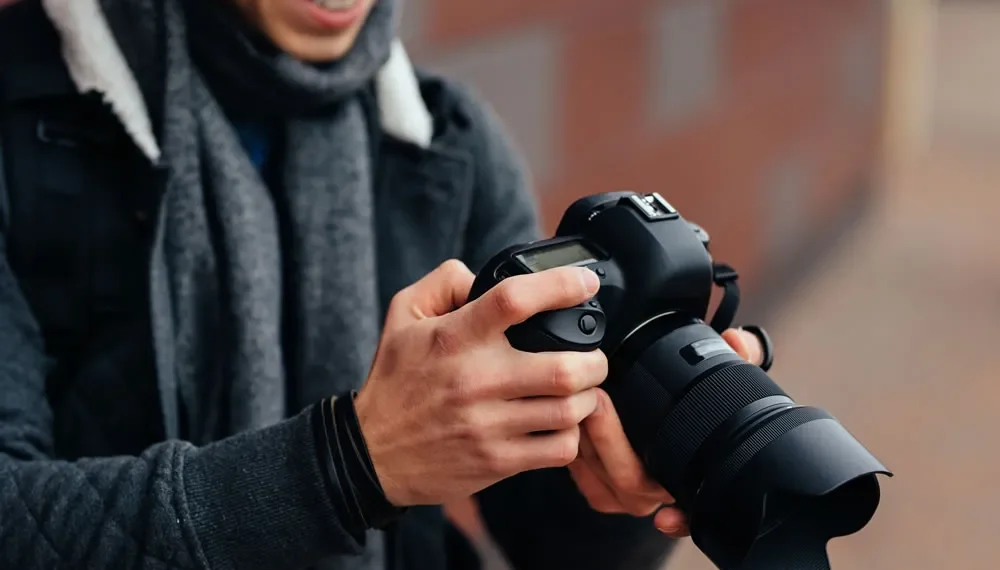 Photographer reviewing photos on a DSLR camera outdoors