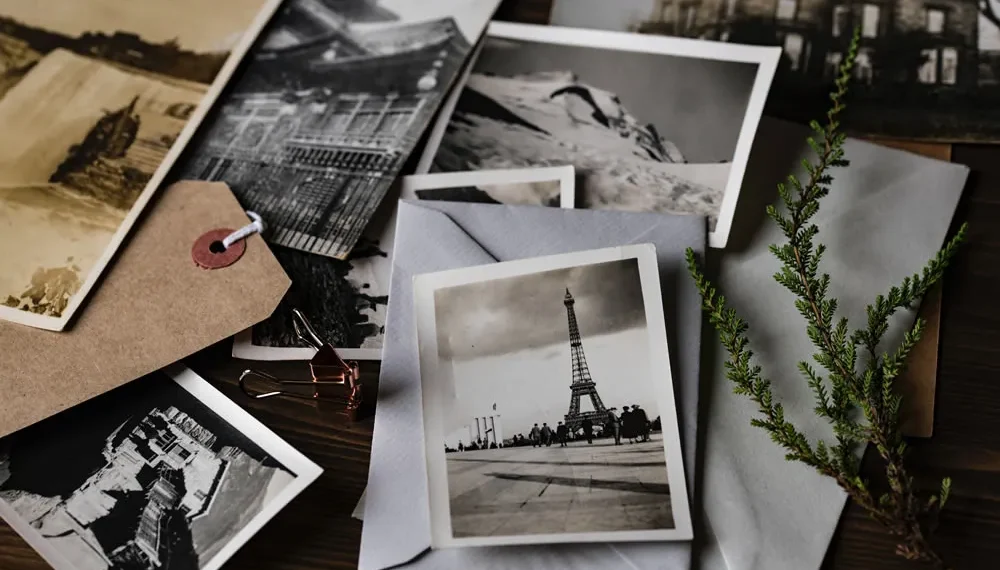 Vintage photos scattered with envelope, tag, and plant on table