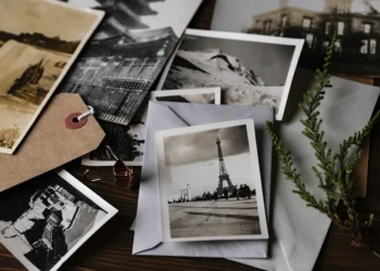 Vintage photos scattered with envelope, tag, and plant on table