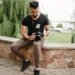 Male photographer sitting on a stone wall reviewing shots on his DSLR camera