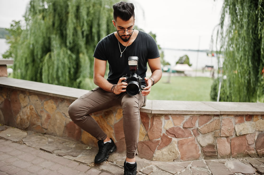 Premium Photo | Handsome young photographer poses with smiles and holding  professional digital camera in the studio