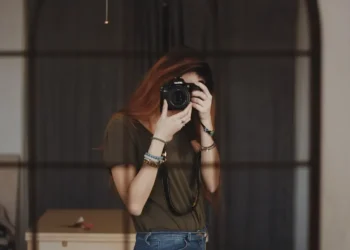 A girl taking a mirror selfie with a DSLR camera, face obscured by the lens