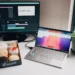 Desk with video editing software on monitor, laptop, box of donuts, and plant