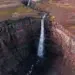 Aerial view of a waterfall plunging into a red-layered canyon