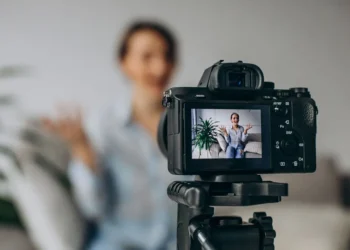 Woman recording herself on a tripod-mounted camera, visible on the LCD screen