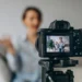 Woman recording herself on a tripod-mounted camera, visible on the LCD screen