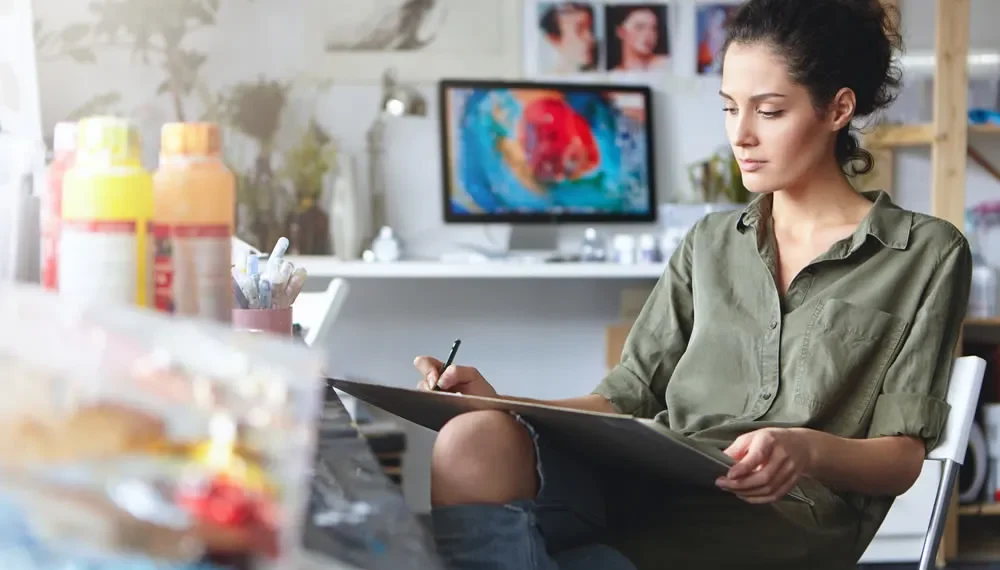 Female artist sketching on a clipboard in a creative studio workspace
