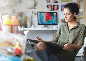 Female artist sketching on a clipboard in a creative studio workspace